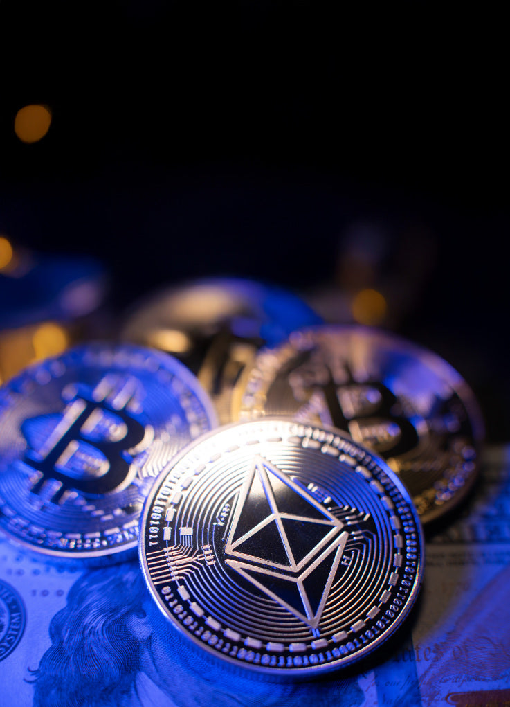 Nahaufnahme glänzender Bitcoin- und Ethereum-Münzen auf einem US-Dollar-Schein mit dunklem Hintergrund.
