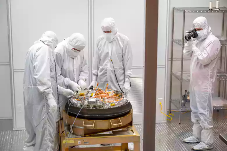 In Schutzanzügen gekleidete Nasa Mitarbeiter betrachten die Kapsel einer Nasa-Mission