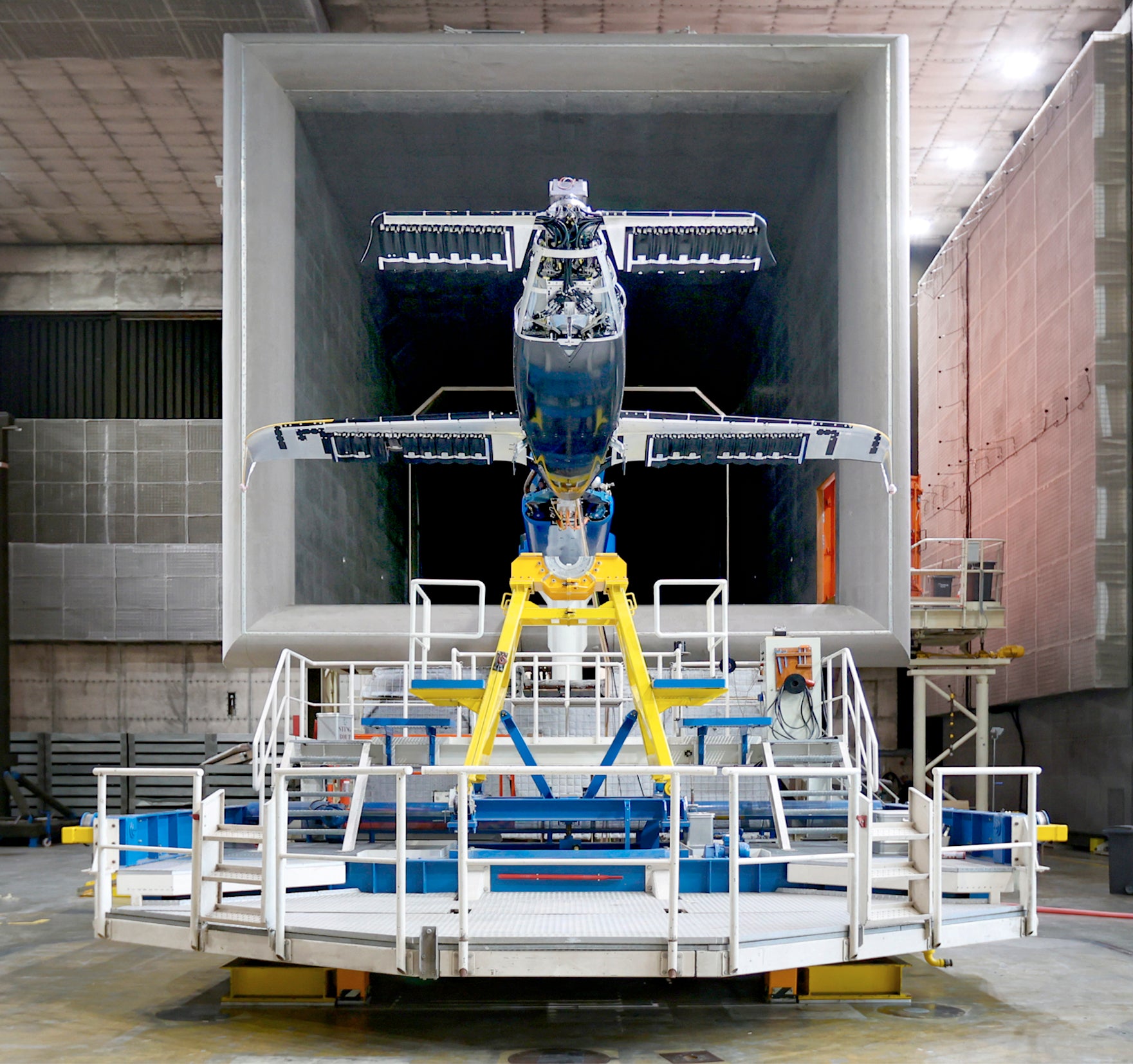 Teilweise montiertes Flugzeug in einem großen Windkanal für aerodynamische Tests, aufgenommen frontal auf der Testplattform.